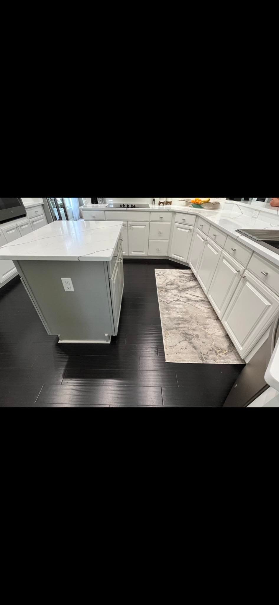 Kitchen with gray cabinets, white countertops, dark wood floor, and an area rug.