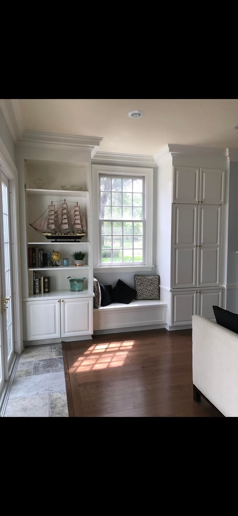 Built-in white bookshelves with a window seat in a room with hardwood floors.