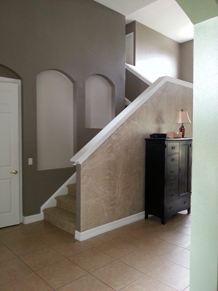 Entryway with stairs, brown walls, built-in alcoves, white trim, beige tile floor, and a black cabinet.