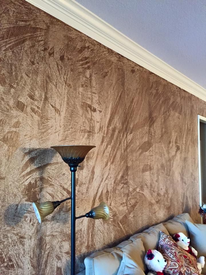 Brown textured wall with white crown molding, a floor lamp, and a beige sofa.