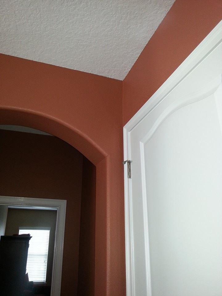 Interior view of archway and doorway with rust-colored walls, white trim and door, and white ceiling.