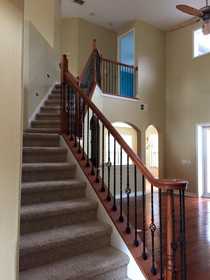 A staircase with carpeted steps and a wooden railing leads to a second floor. The wall is painted a light yellow.