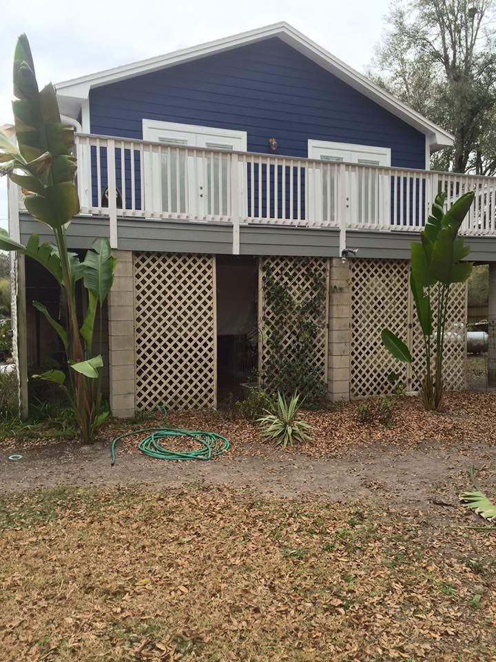 Blue house with a raised deck, lattice undercarriage, and tropical plants.