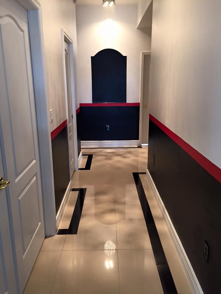 Hallway with beige tiled floor, black and red wall accents, and white doors.