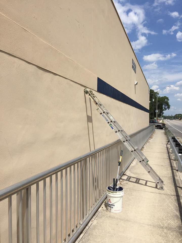 Ladder leaning against a building's wall, next to a ramp with a metal railing.