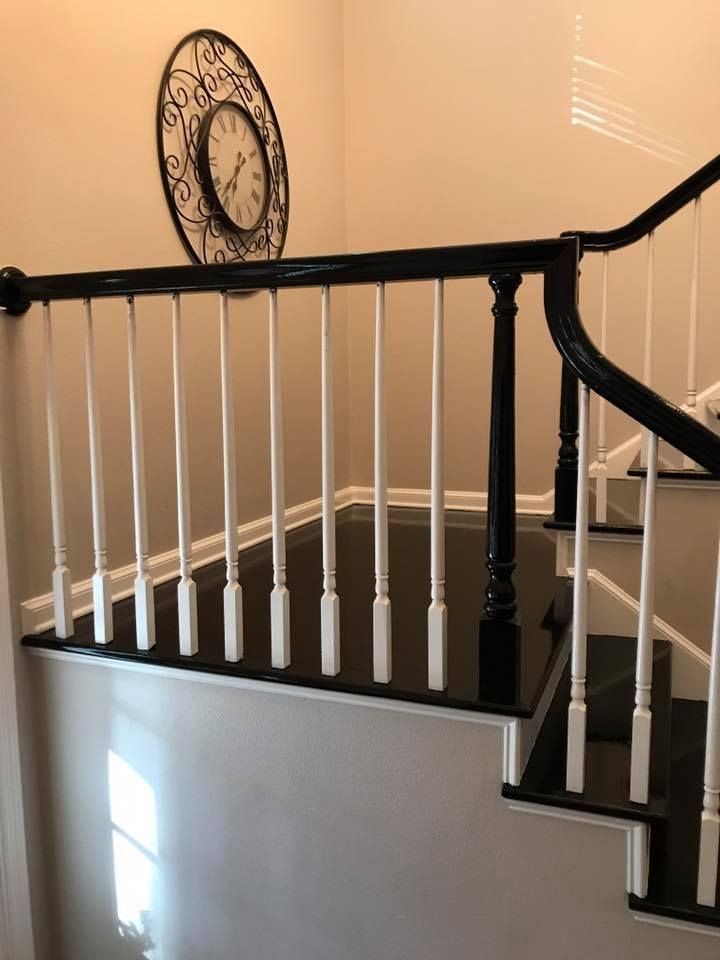 Black and white staircase with spindles. A clock hangs on the beige wall.