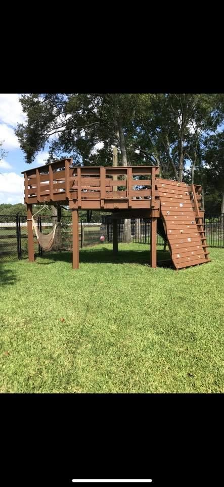 Staircase with dark wooden handrails, black iron balusters, and a ladder leaning against the wall during renovation.