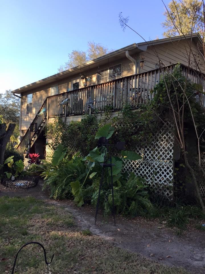 Staircase with light wood steps, white spindles, and black railing. A clock hangs on the beige wall.