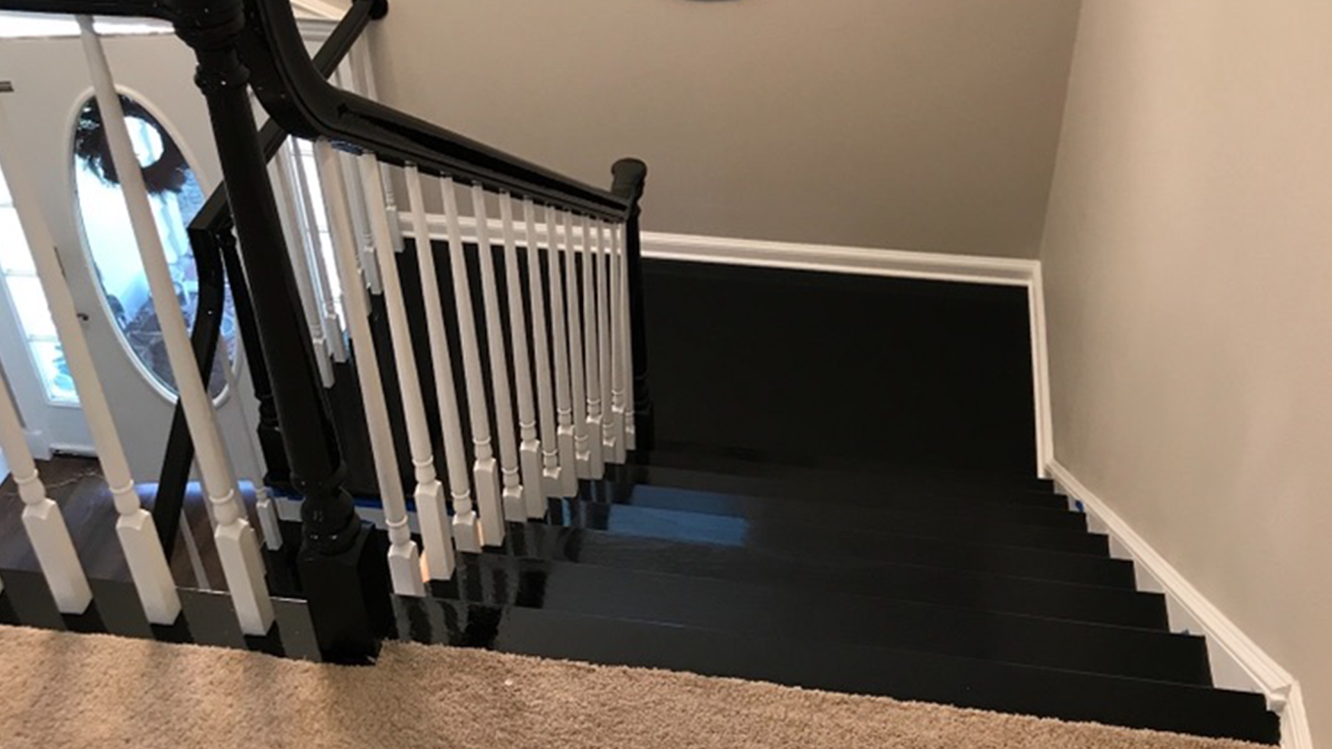 Top-down view of black painted staircase with white balusters and black railing.