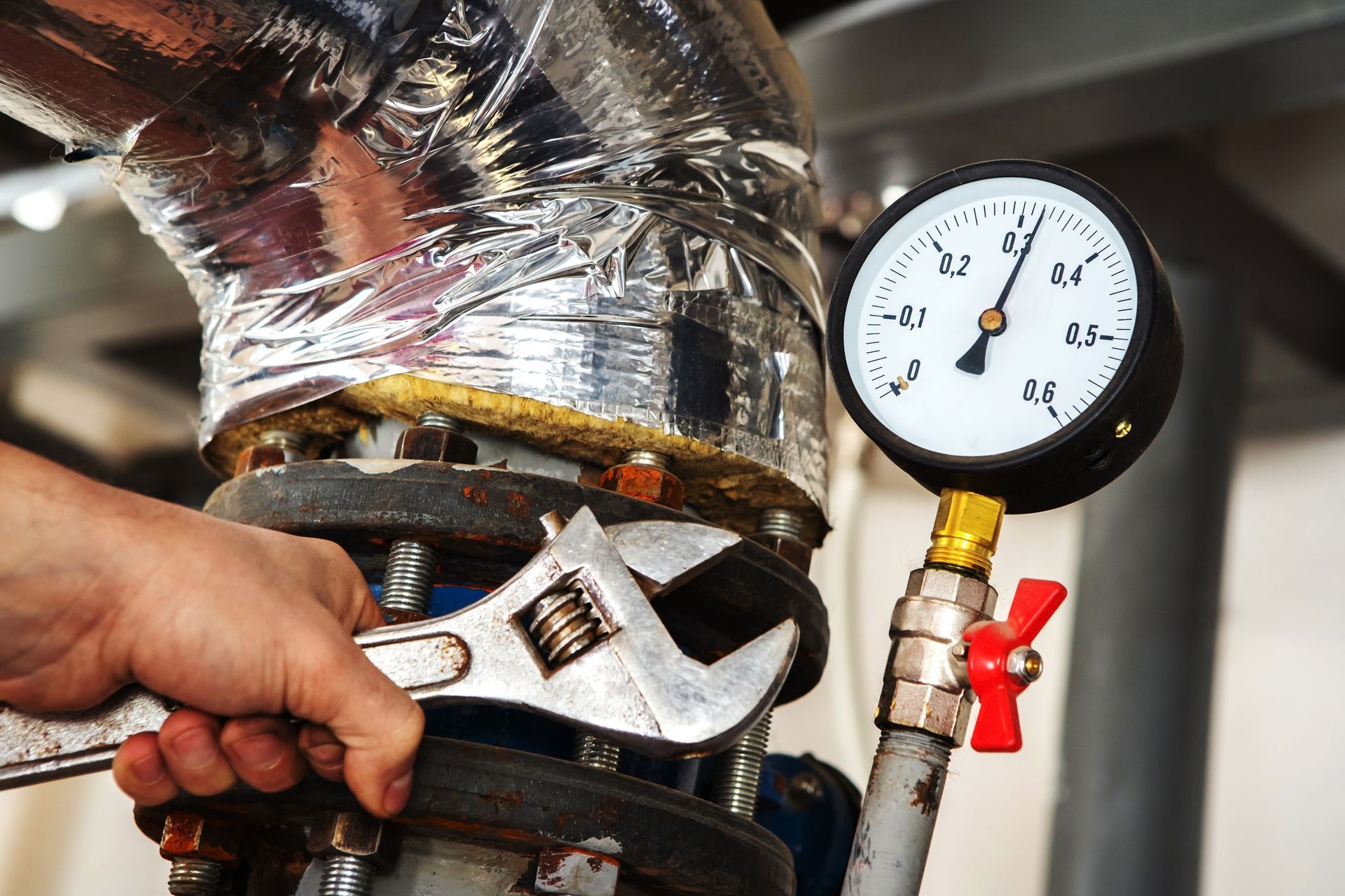 Technician performing maintenance and repair work inside an industrial boiler room, inspecting equipment and pipelines.