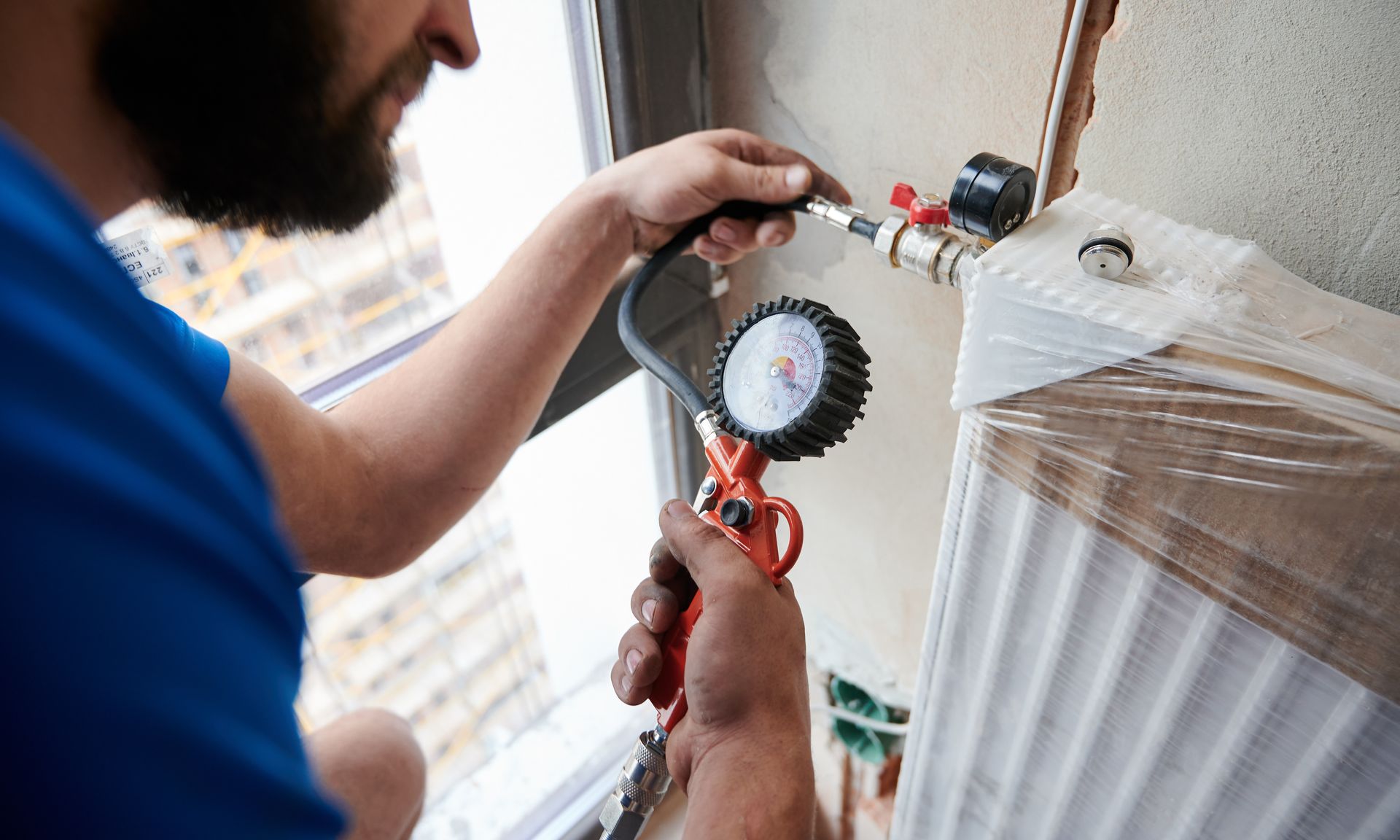 a plumber using an air compressor to fill pipes with pressurized air for leak inspection in a new installation.