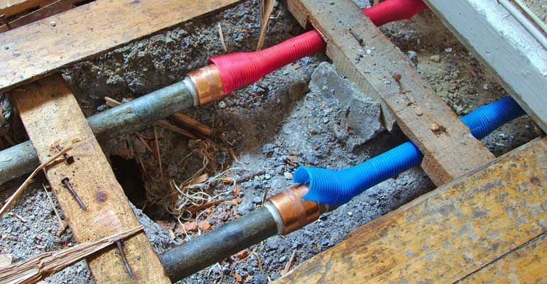A man wearing a mask is working on pipes.