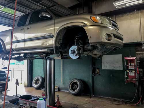 A truck is sitting on a lift in a garage.