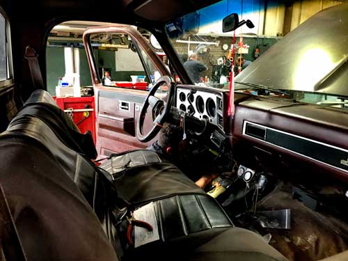 The inside of a car with the hood open in a garage.