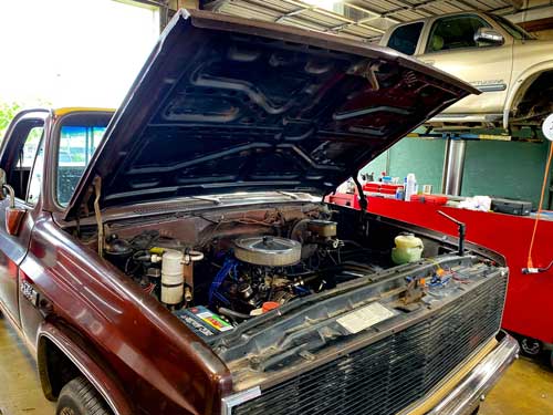 The hood of a truck is open in a garage.