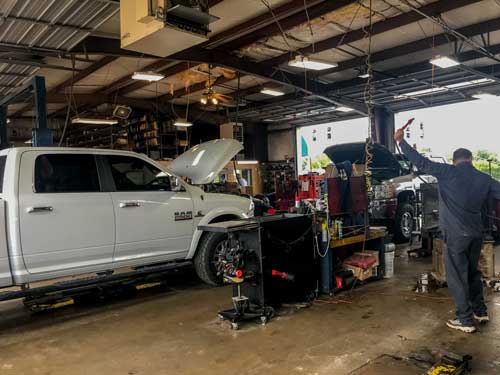 A man is working on a white truck in a garage.