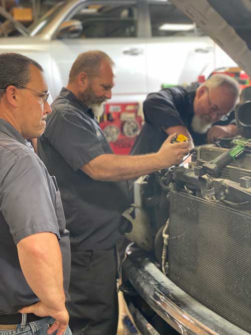 A group of men are working on a truck in a garage.