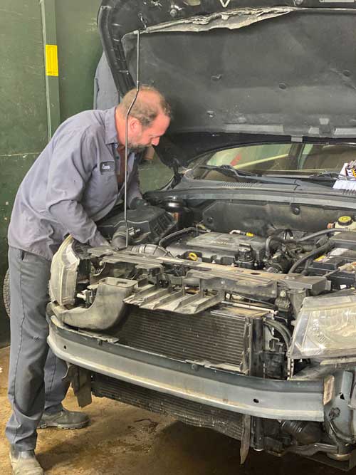 A man is working on the engine of a car in a garage.