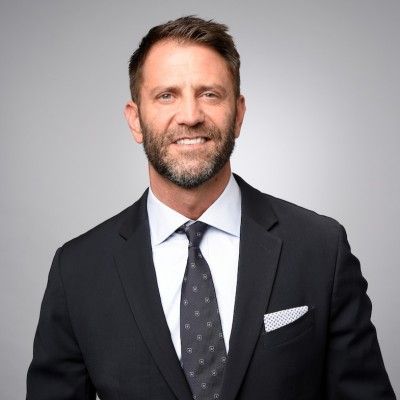 Man in a suit smiles, inside office.