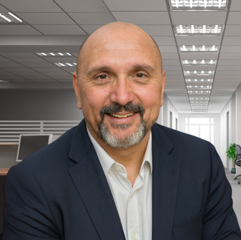 Man in a suit smiles, inside office.