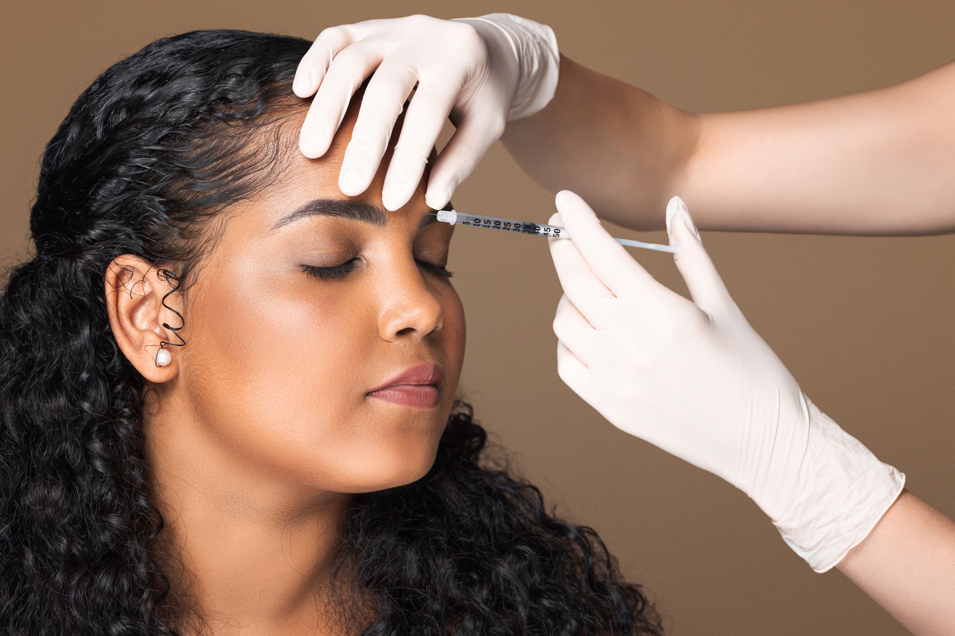 A woman is getting a botox injection in her forehead.