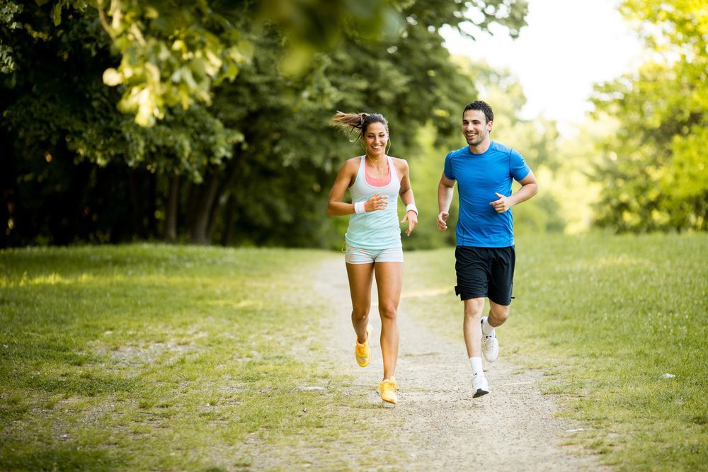 A man and a woman are running in a park.