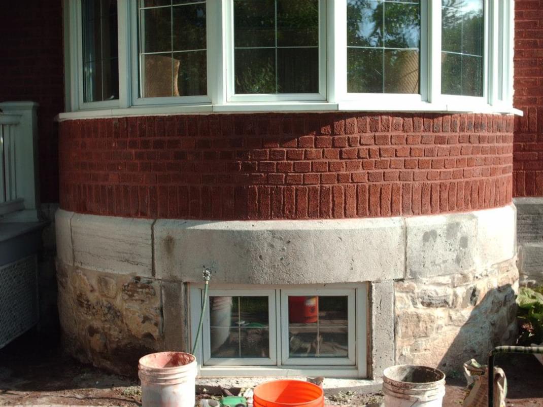 Un bâtiment en brique avec une baie vitrée et des seaux de peinture devant.