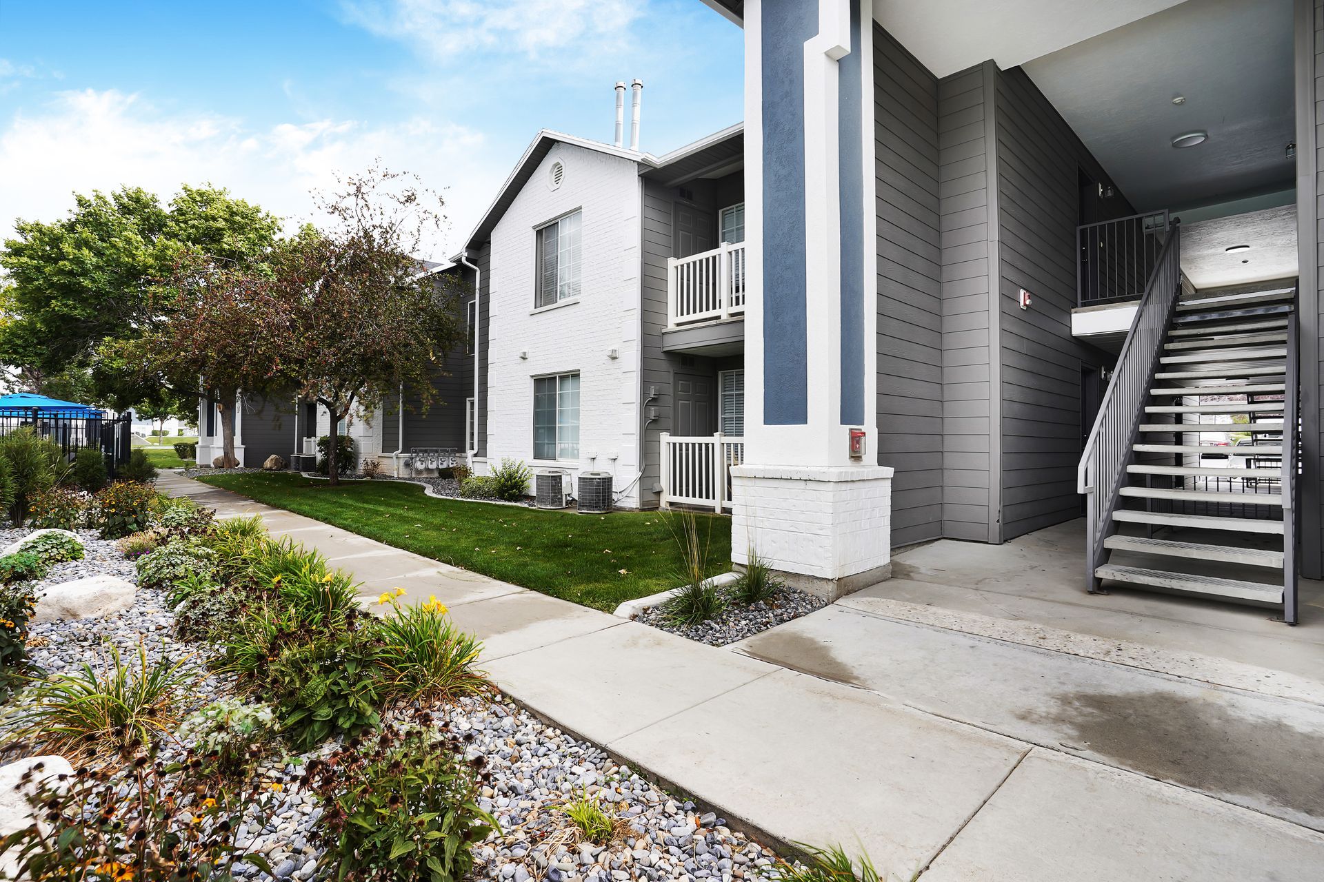 Exterior of the Woodgate apartment building with stairs, walkways, and manicured landscaping.