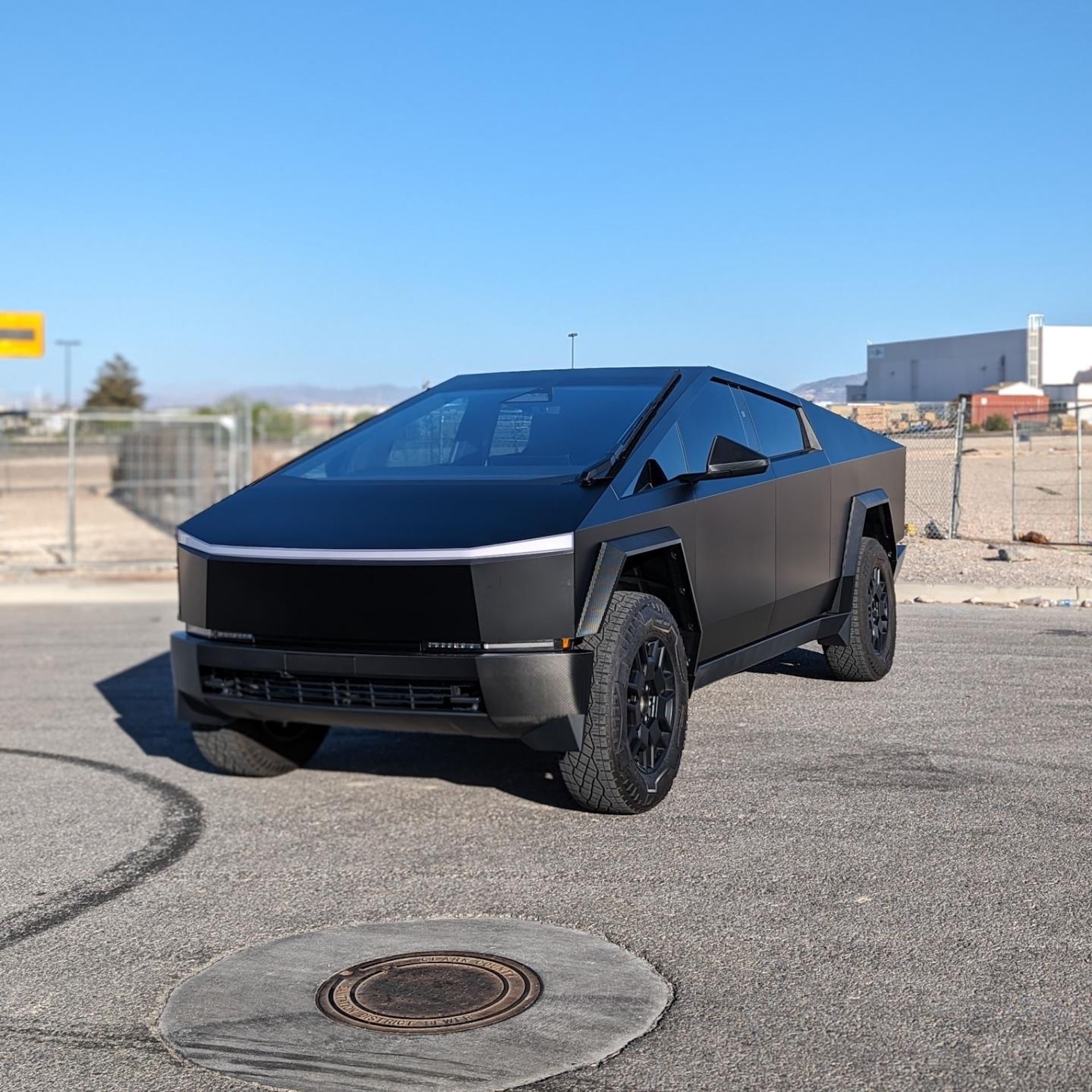 A black tesla cybertruck is parked in a parking lot.