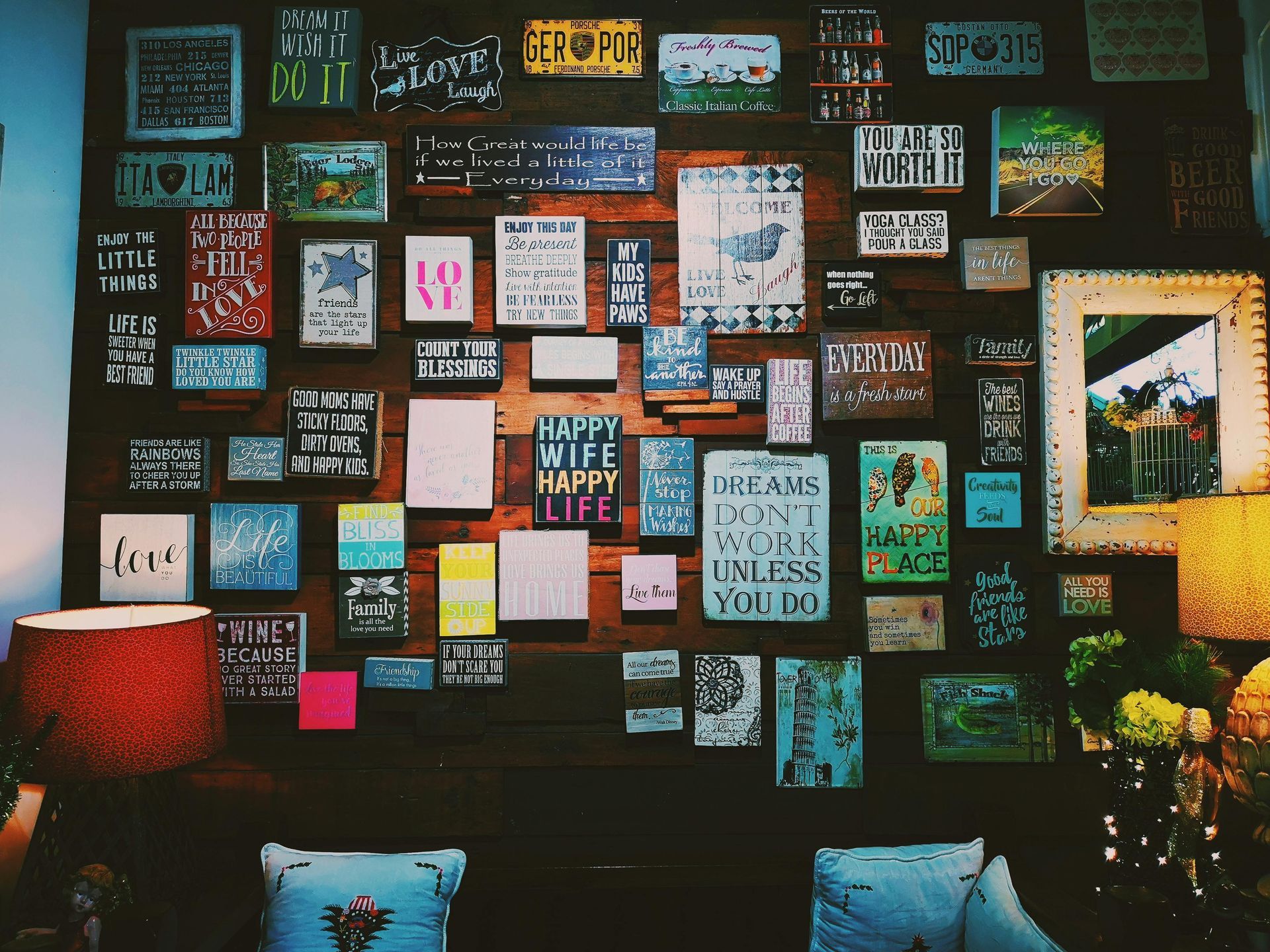 A wall with a lot of pictures on it and a lamp