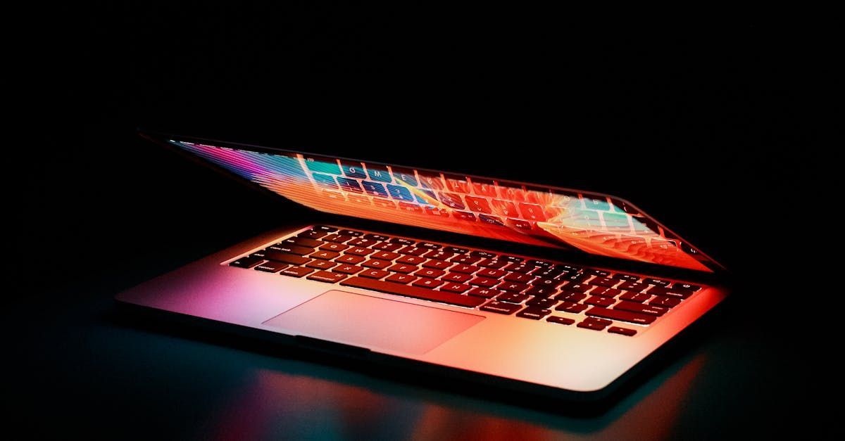 A laptop computer is open and sitting on a table in the dark.