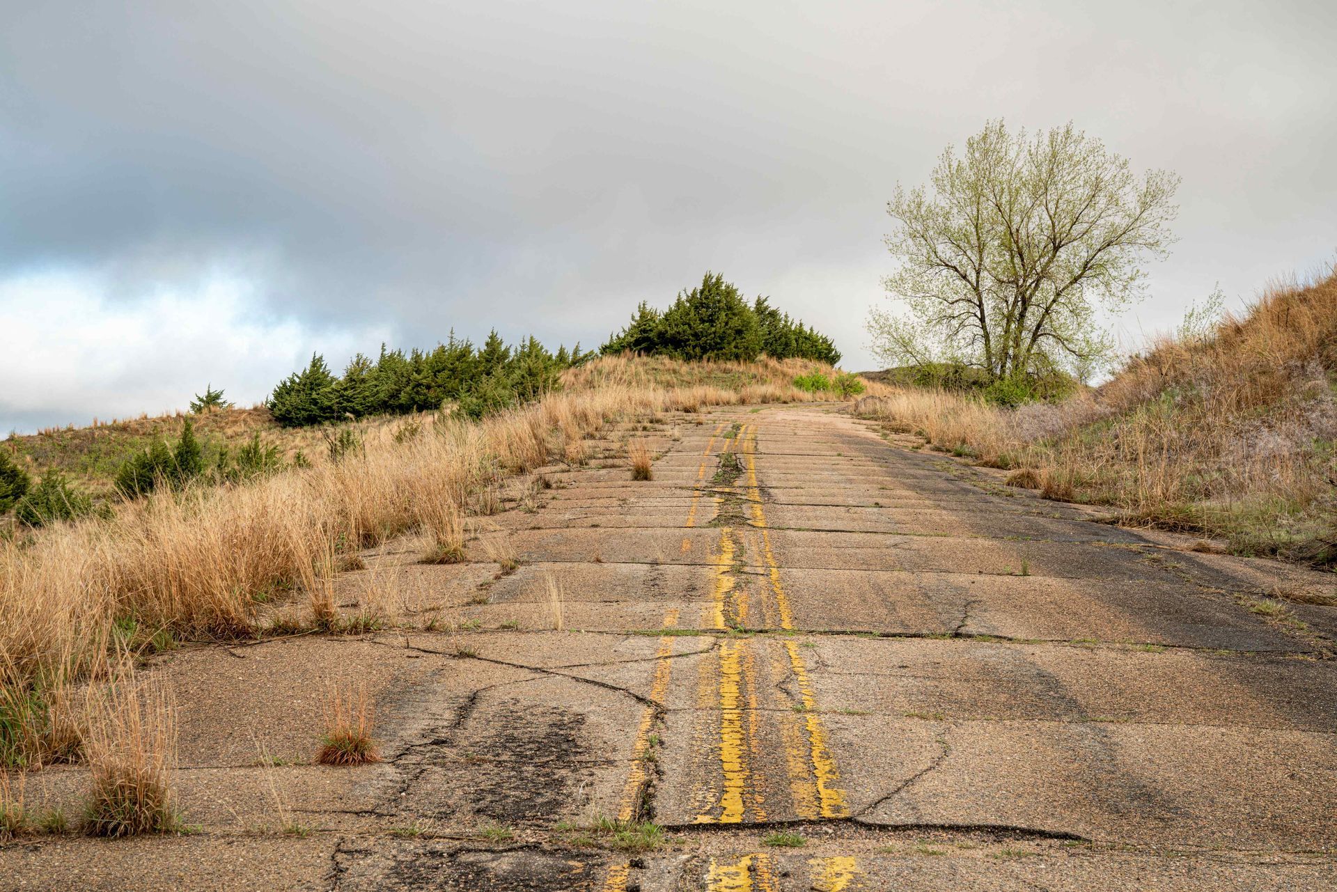 Cracked concrete road ascending a hill 
