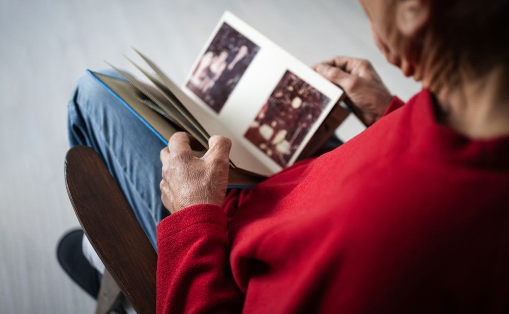 Senior in red shirt looking at old photo album.