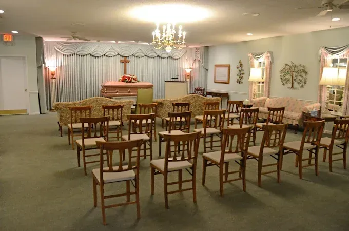 Interior of a funeral home, chairs set for service, altar with cross.