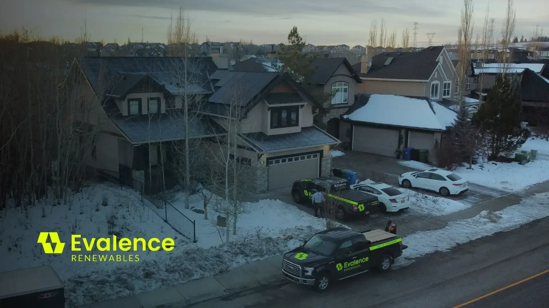Snowy residential street with police vehicles in front of a house.