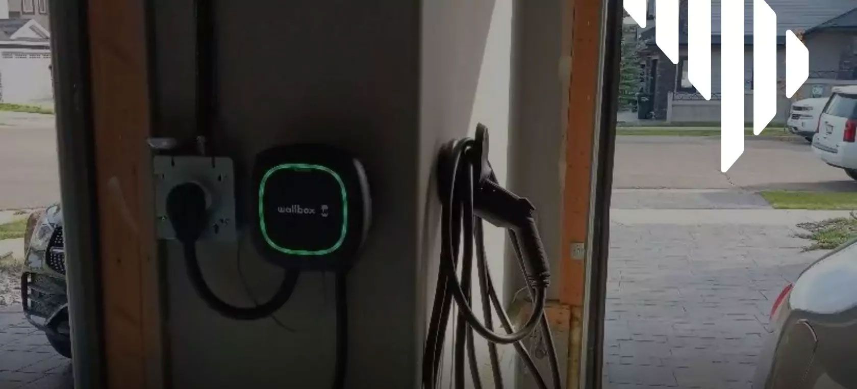 Electric vehicle charger installed in a garage charging cable visible.