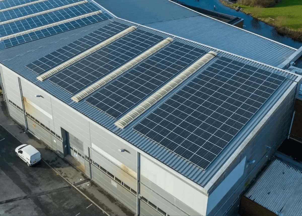 Solar panels on a building's roof, absorbing sunlight. White van parked nearby.