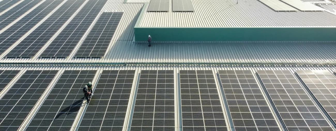 Workers on a rooftop solar panel array on a building.