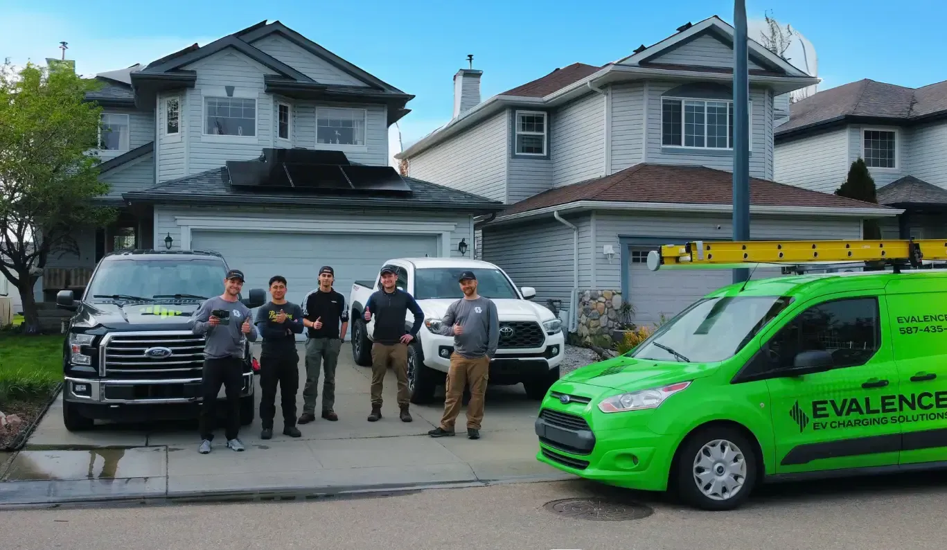 Group of solar installers beside Evalence vehicles in front of suburban houses.