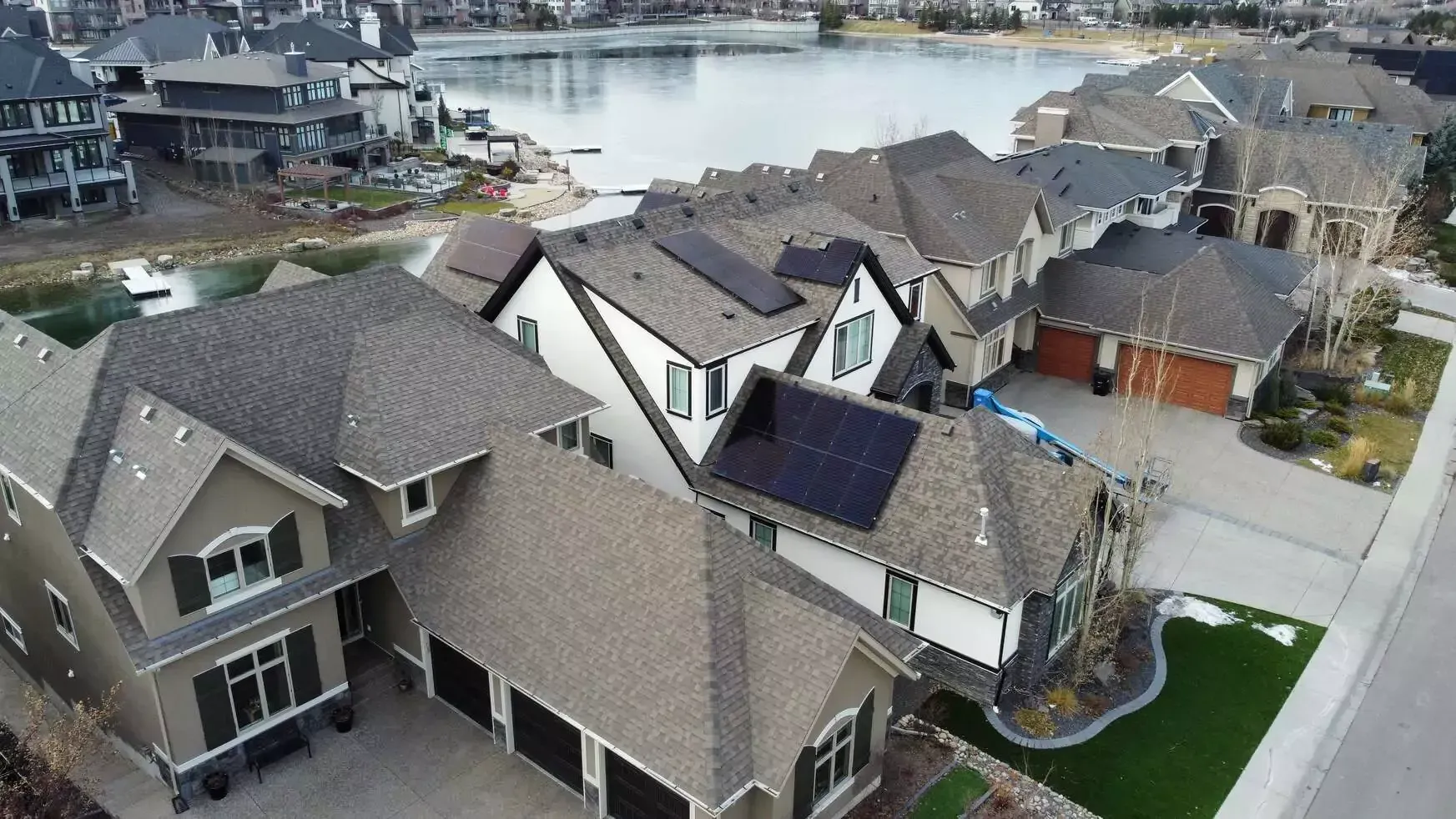 Group of solar installers beside Evalence vehicles in front of suburban houses.