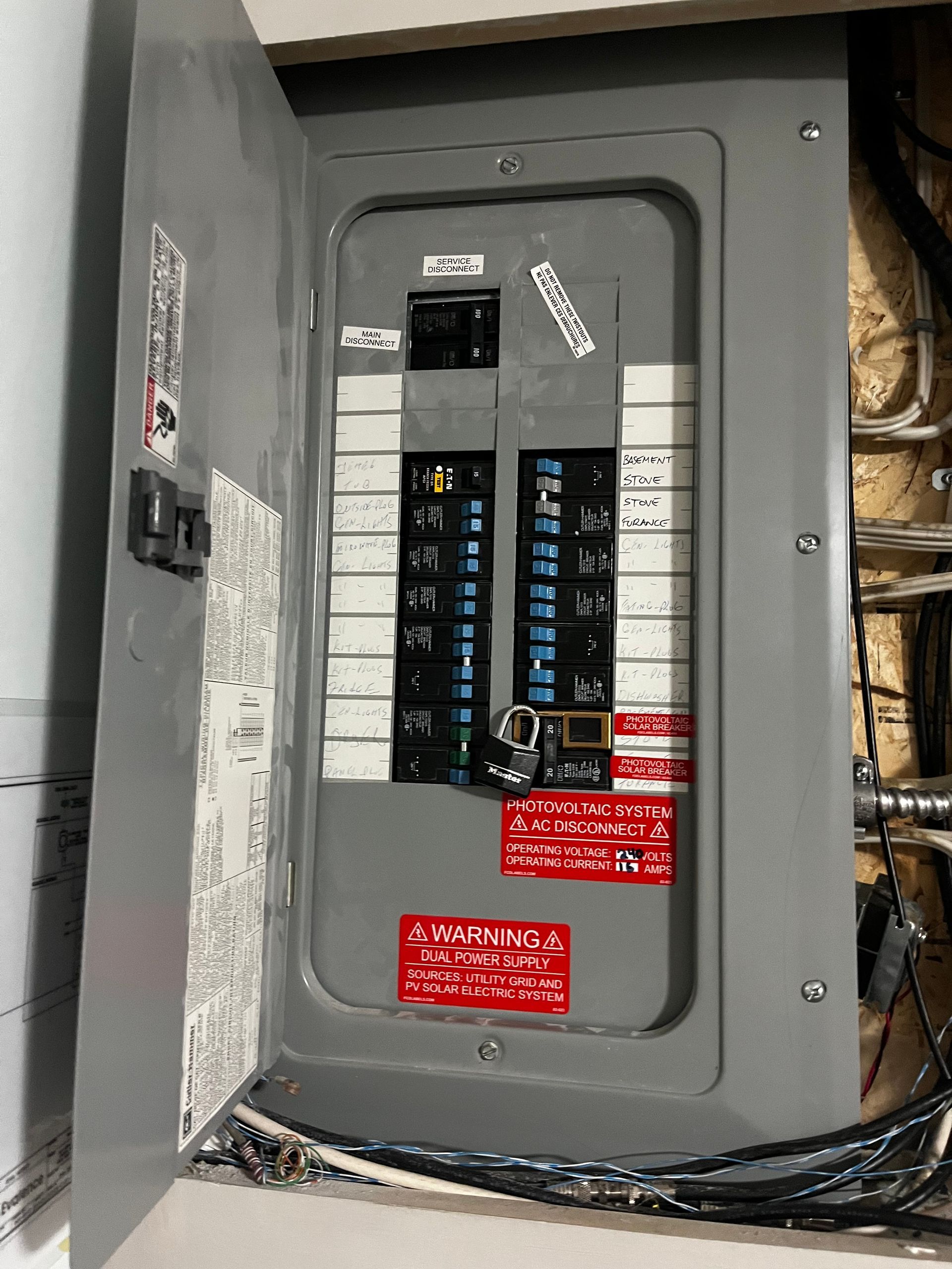 Electrical panel with multiple circuit breakers, some on. Lock and red warning labels are visible.