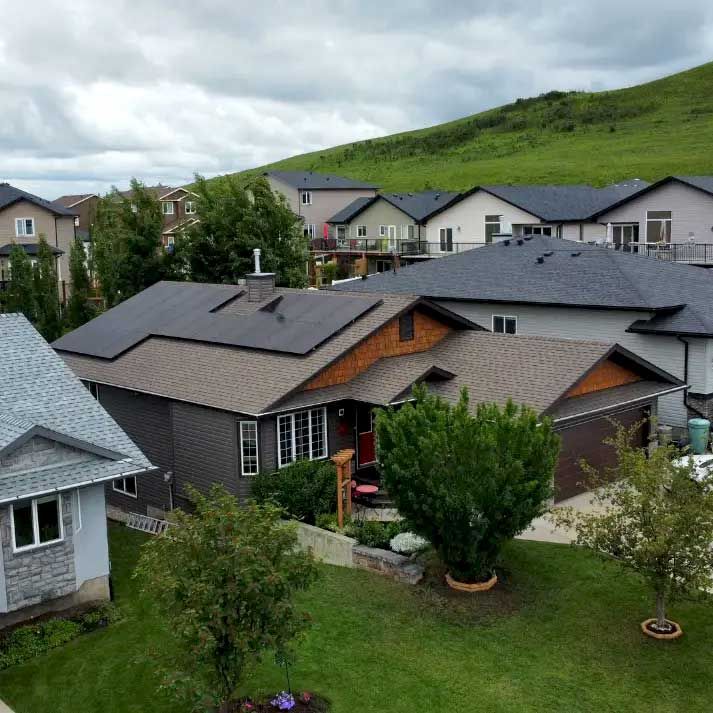 Houses in a residential neighborhood with green lawns and a hillside backdrop on a cloudy day.