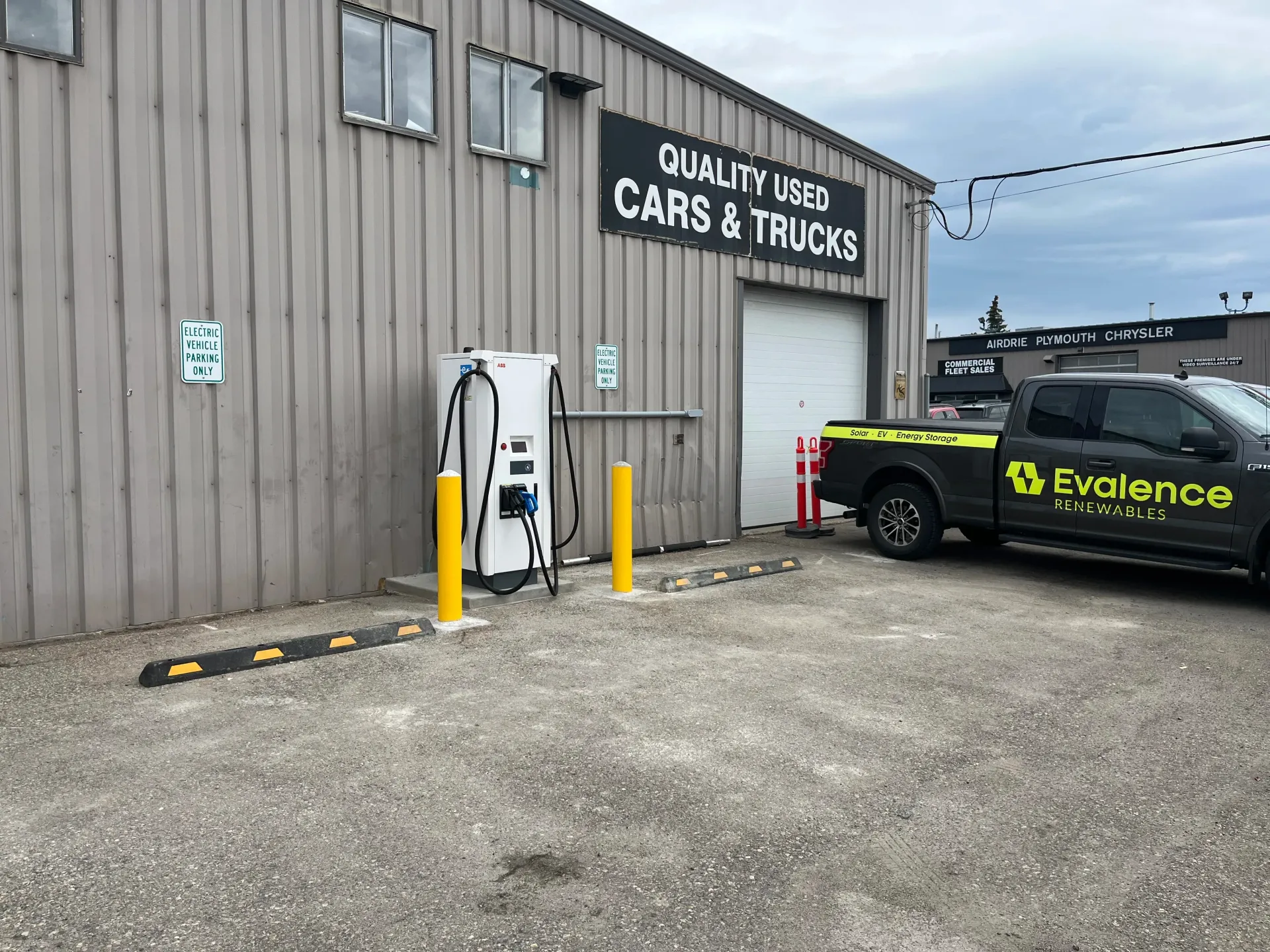 Black electric vehicle charger mounted on a garage wall, cable coiled nearby.