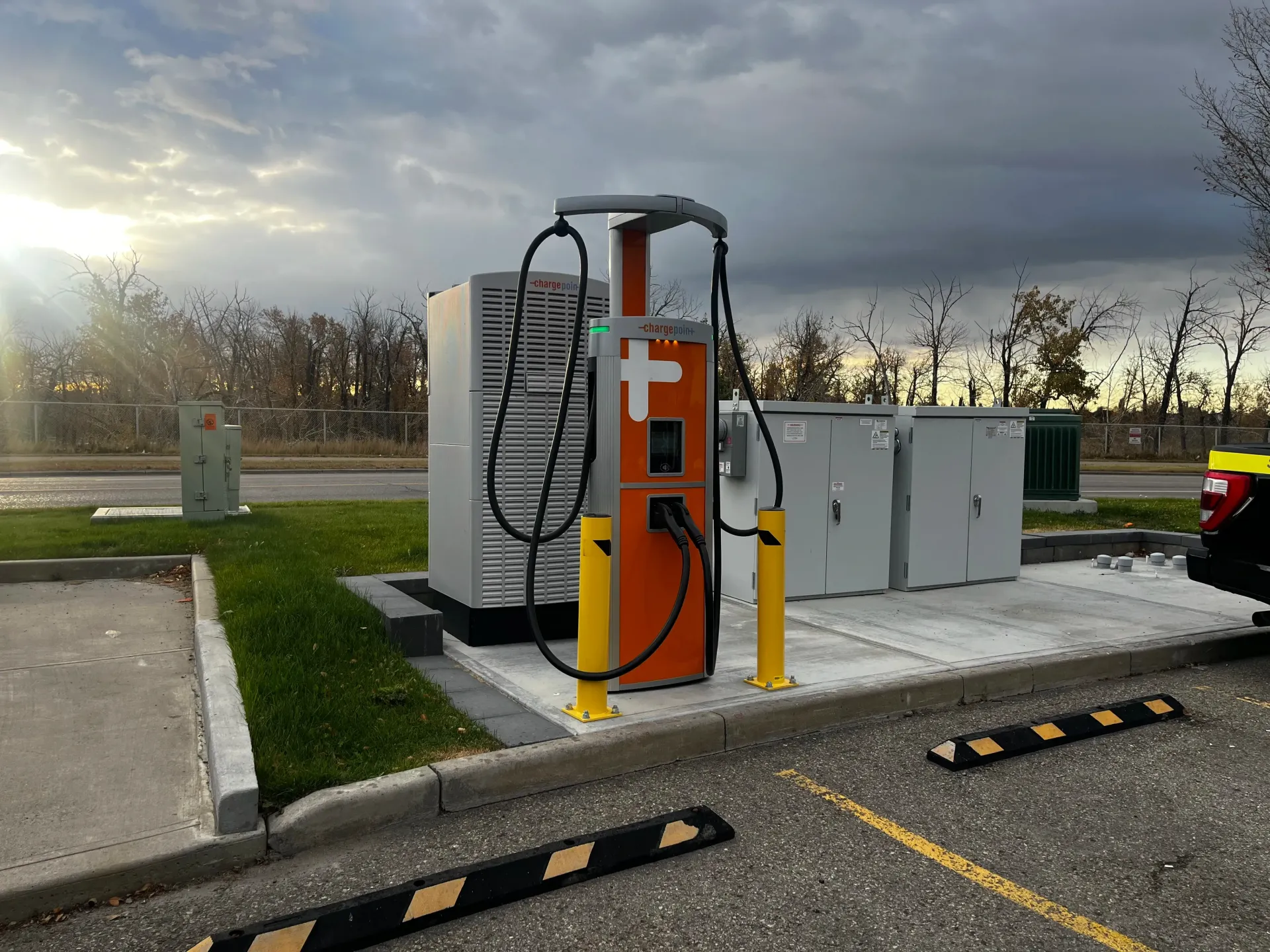 White electric car charger mounted on beige wall, with black charging cable.
