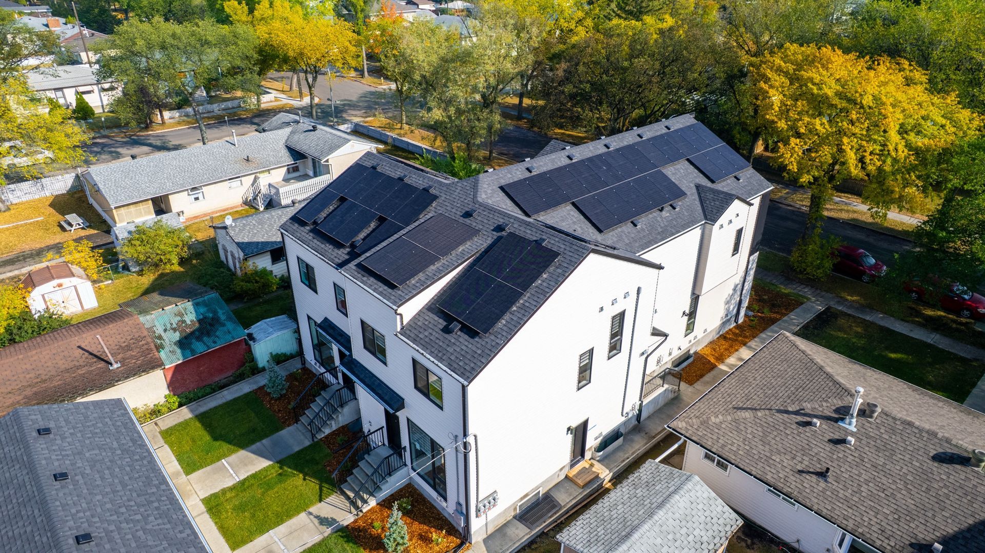 Aerial view of a multi-residential house with solar panels on the roof in a sunny day.