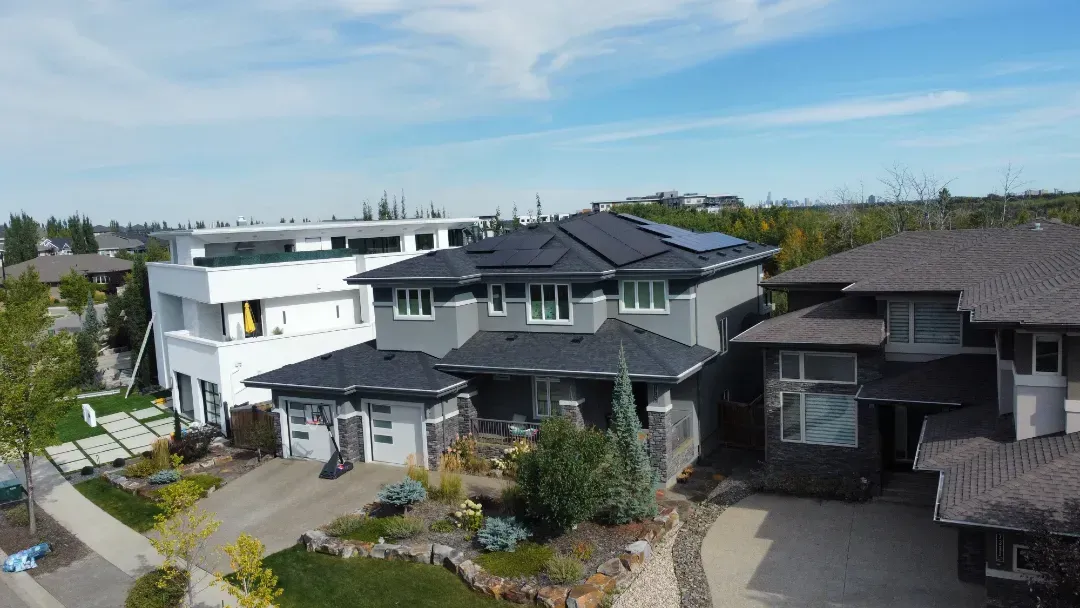 Houses with solar panels on a roof, sunny day, residential neighborhood.