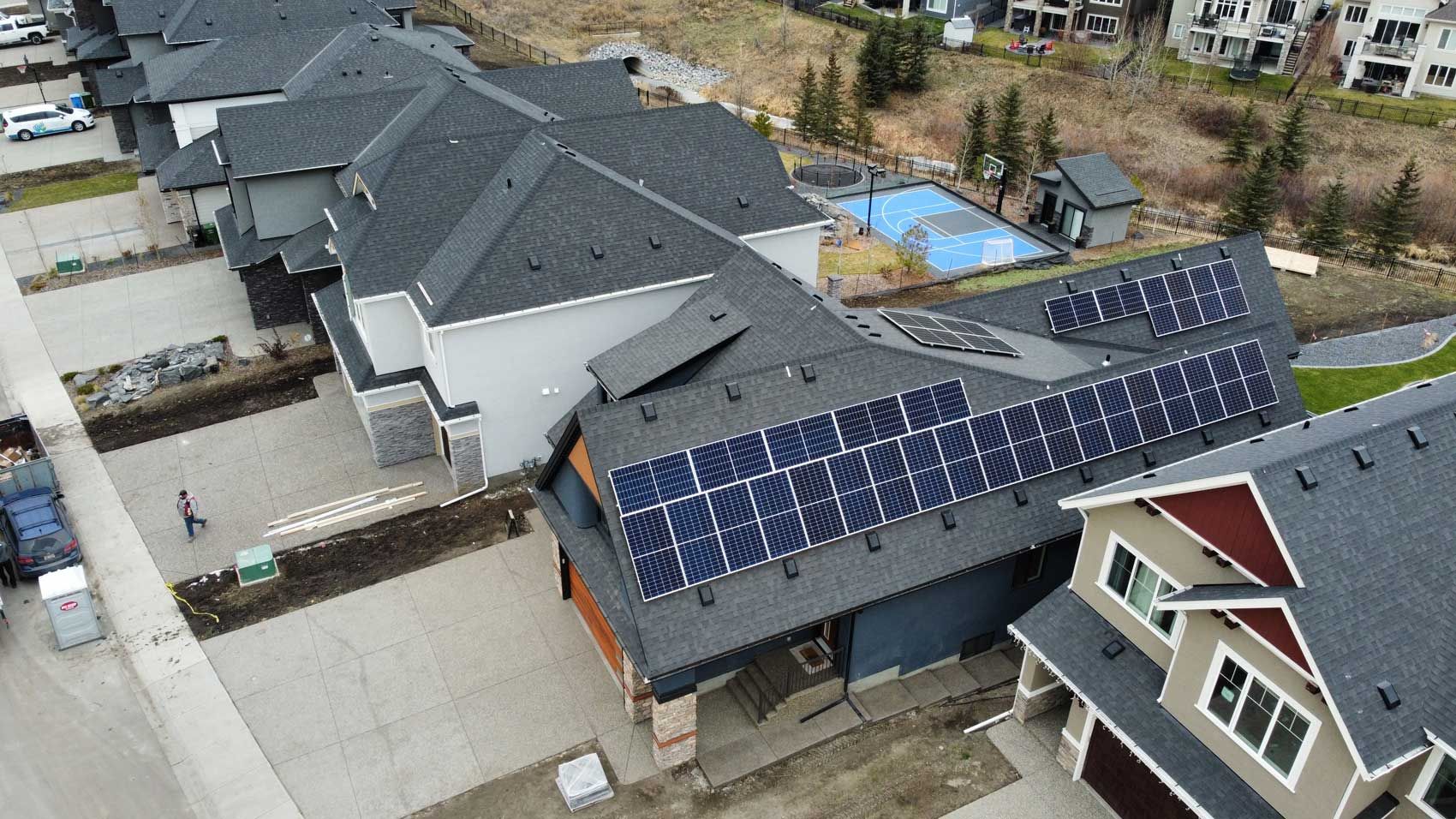 Solar panels on rooftops of several houses in a suburban neighborhood.
