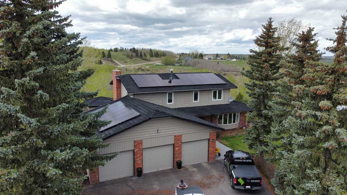 Two-story house with solar panels on the roof, flanked by trees and a three-car garage. A truck is parked in the driveway.