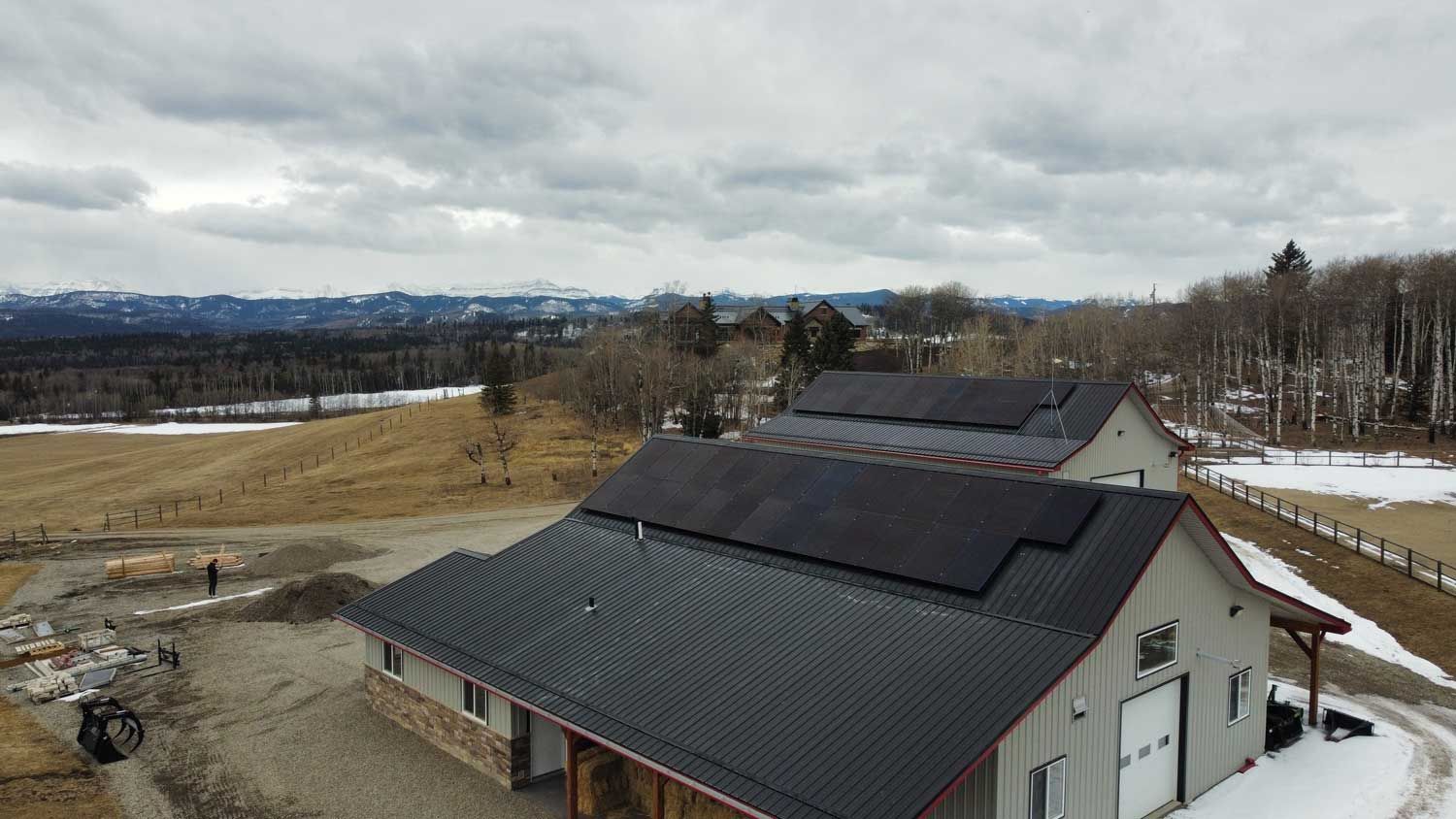 Solar panels on commercial roof with a field and mountains in the background. 