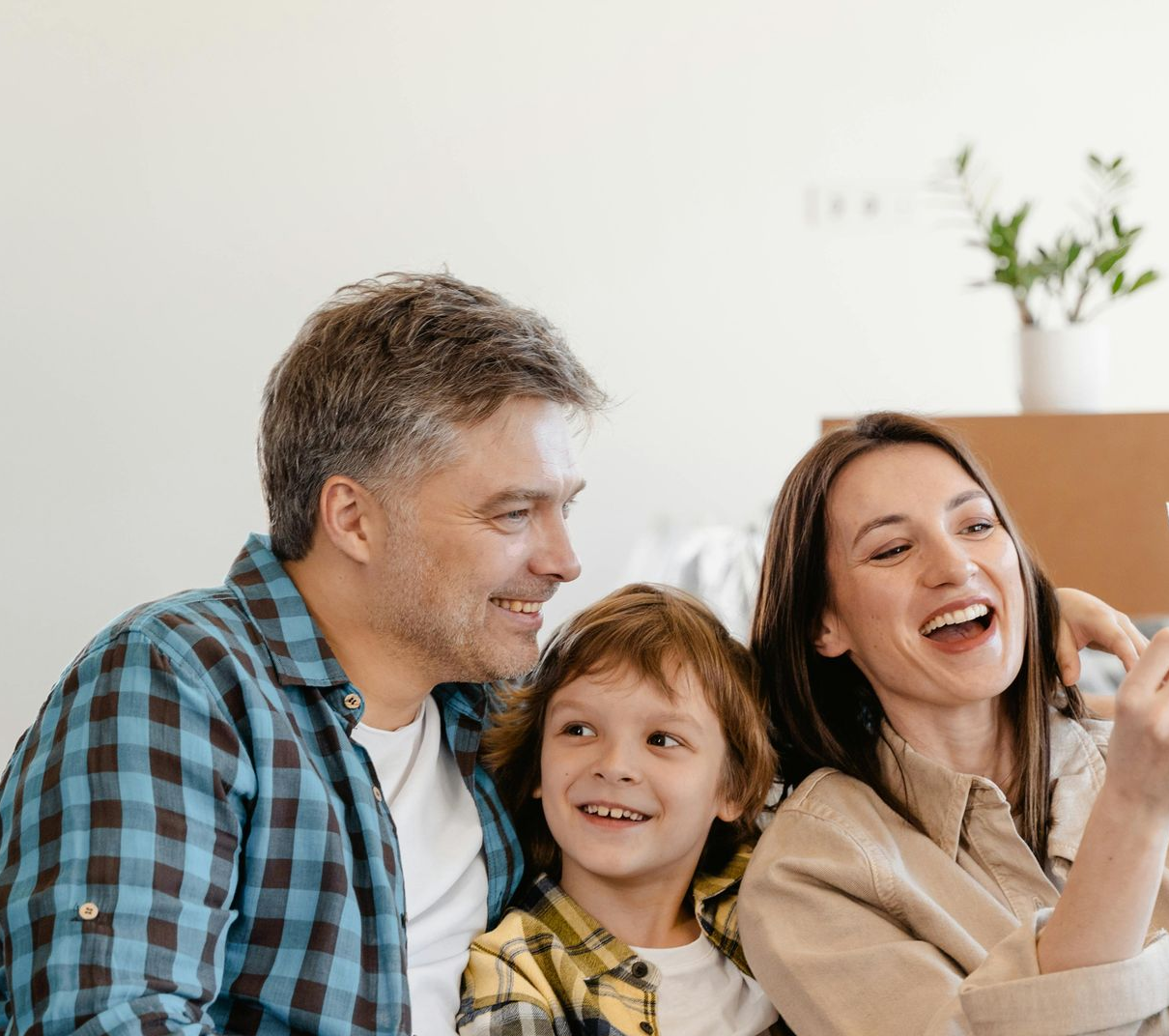 Family smiling and laughing together; an adult arm is around a woman's shoulder.